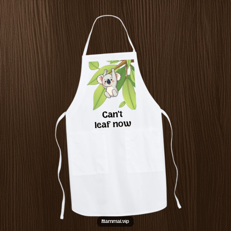 Funny apron featuring a cheerful koala hanging upside down from a giant eucalyptus leaf, adding humor to kitchen tasks.