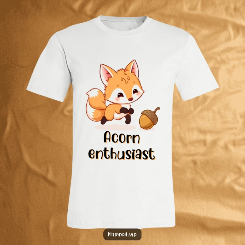 Funny Fox Cub T-Shirt featuring a playful cub with a wagging tail, enthusiastically pursuing a bouncing acorn in a whimsical forest scene.